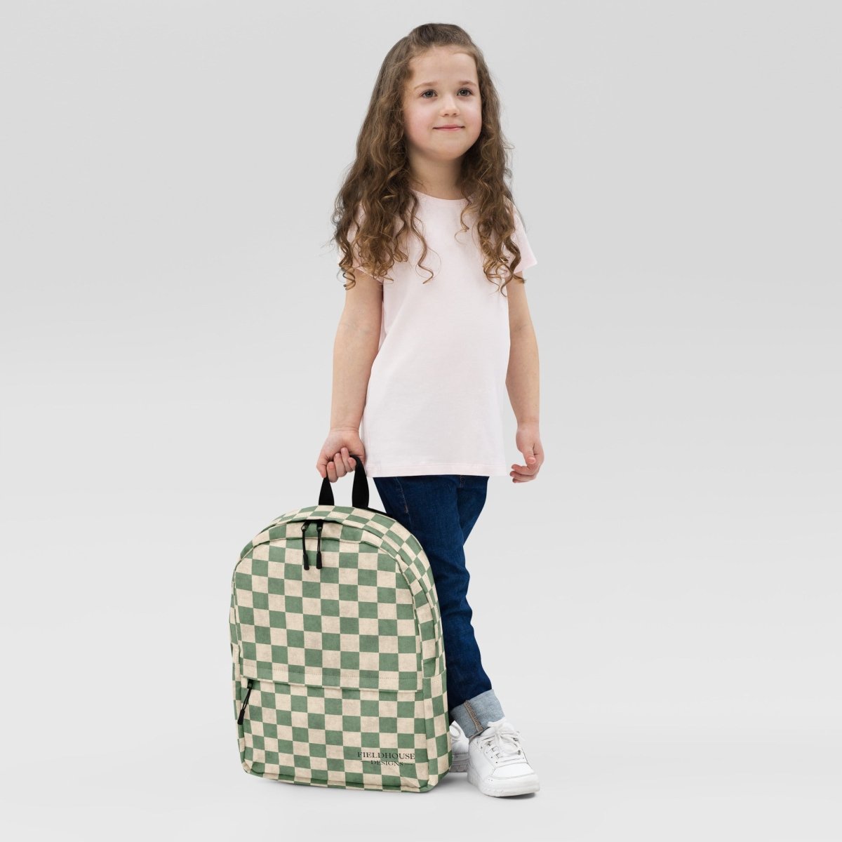 Child holding a green and white checkered backpack against a plain background
