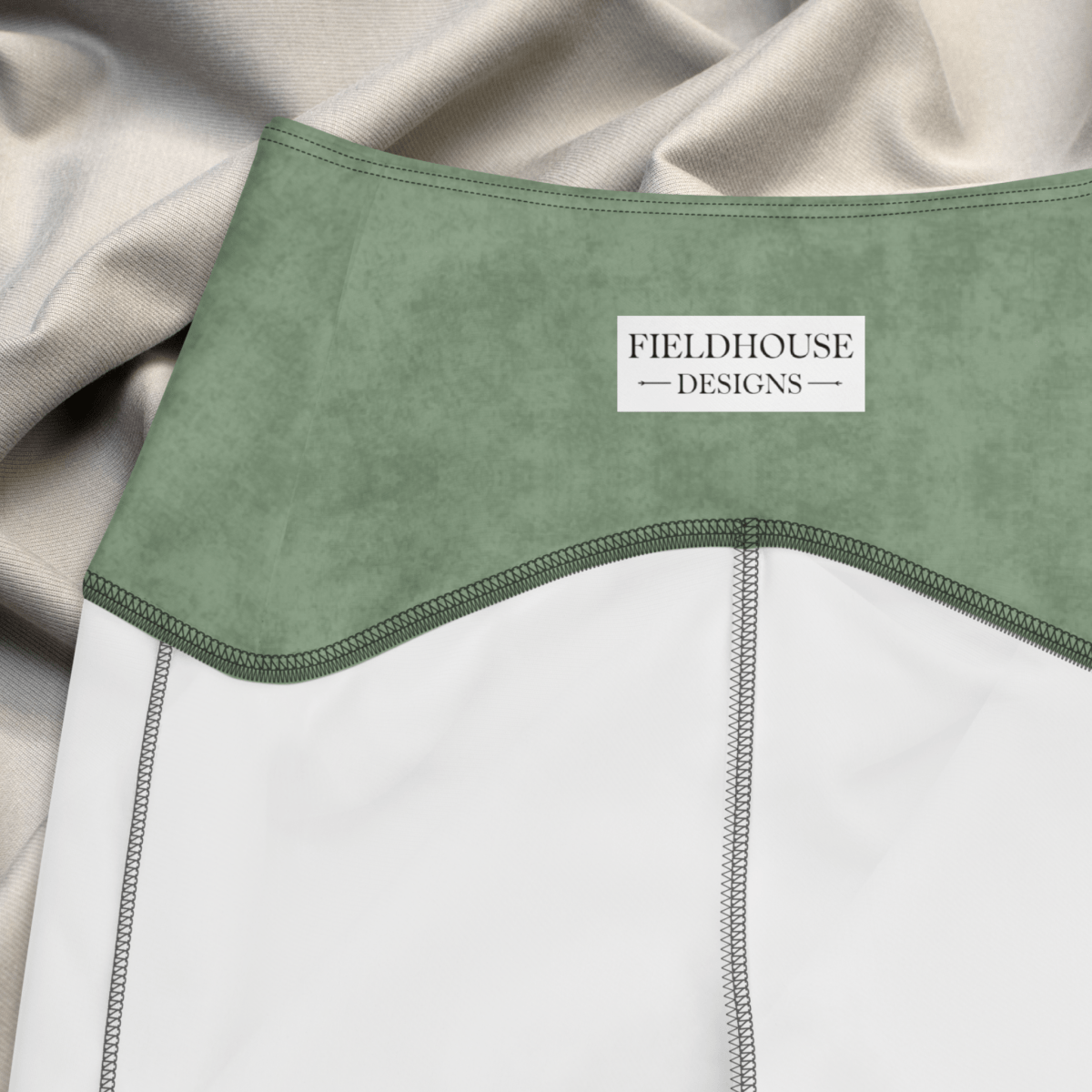 Green garment with 'Fieldhouse Designs' label on a beige and white background
