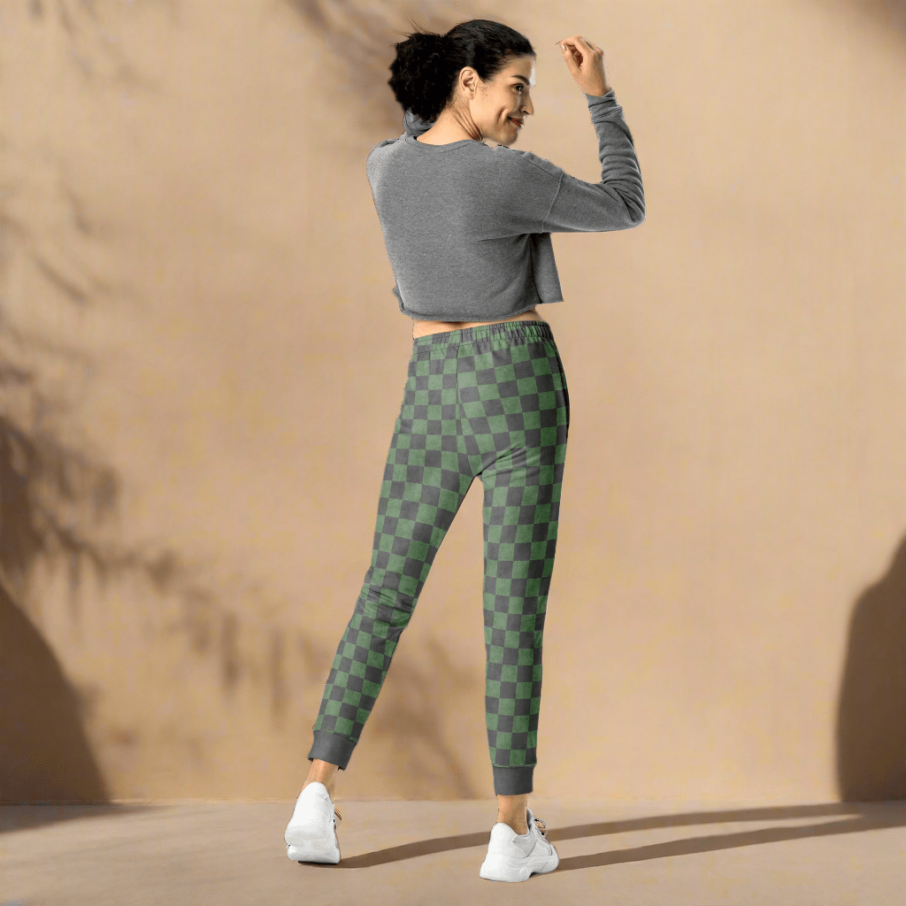 Woman wearing a gray cropped top and green checkered leggings on a neutral background