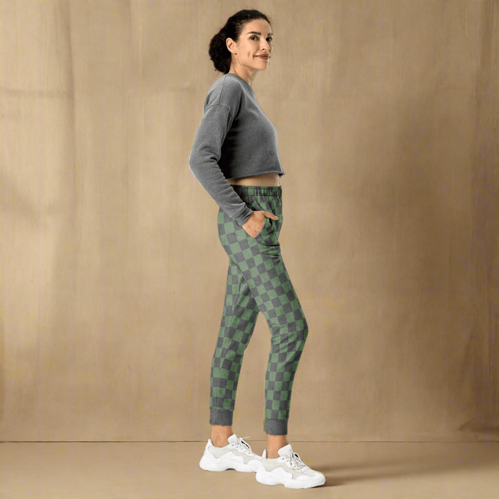 Woman wearing a gray sweatshirt and green checkered pants on a neutral background