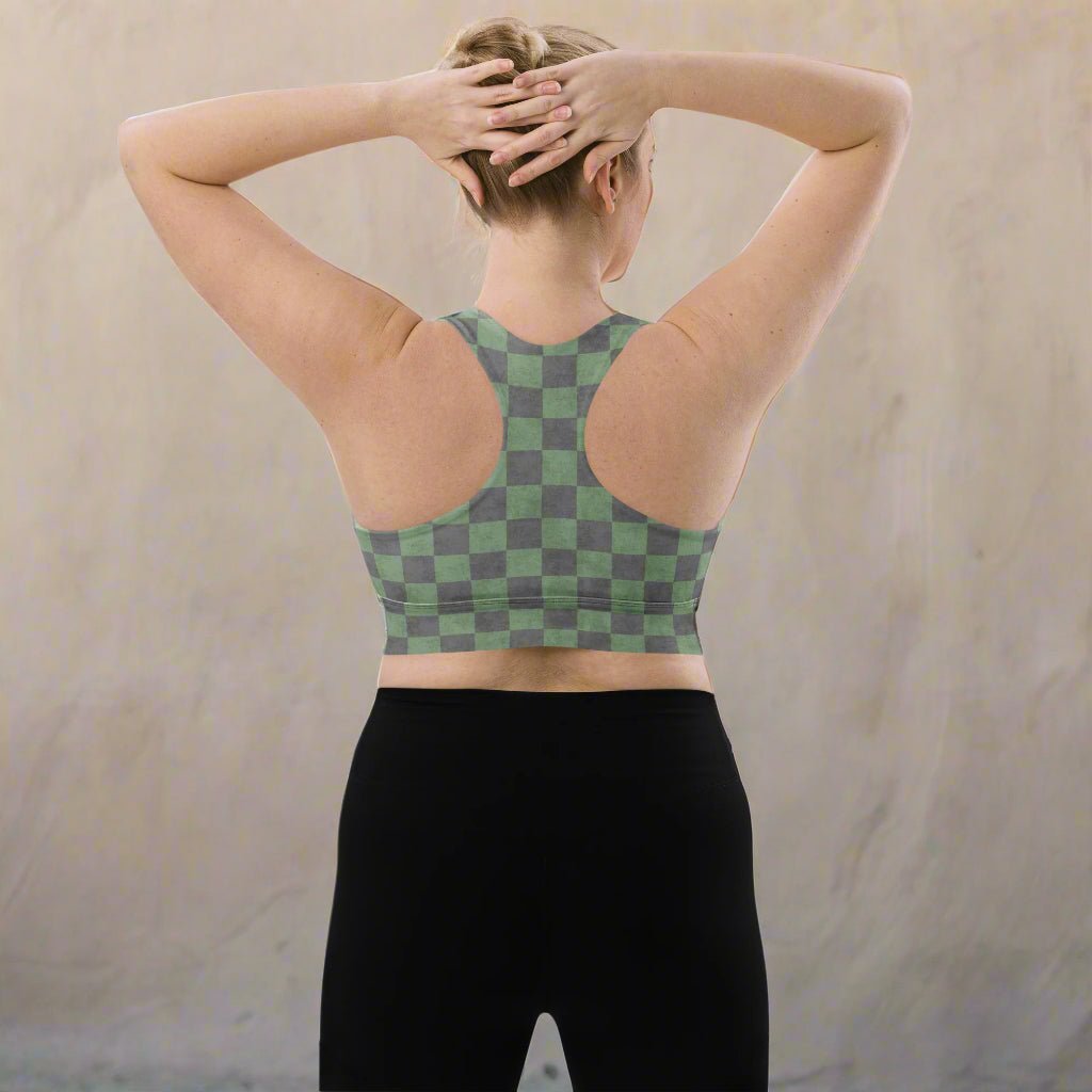 Person wearing a green and gray checkered sports bra and black leggings against a beige background