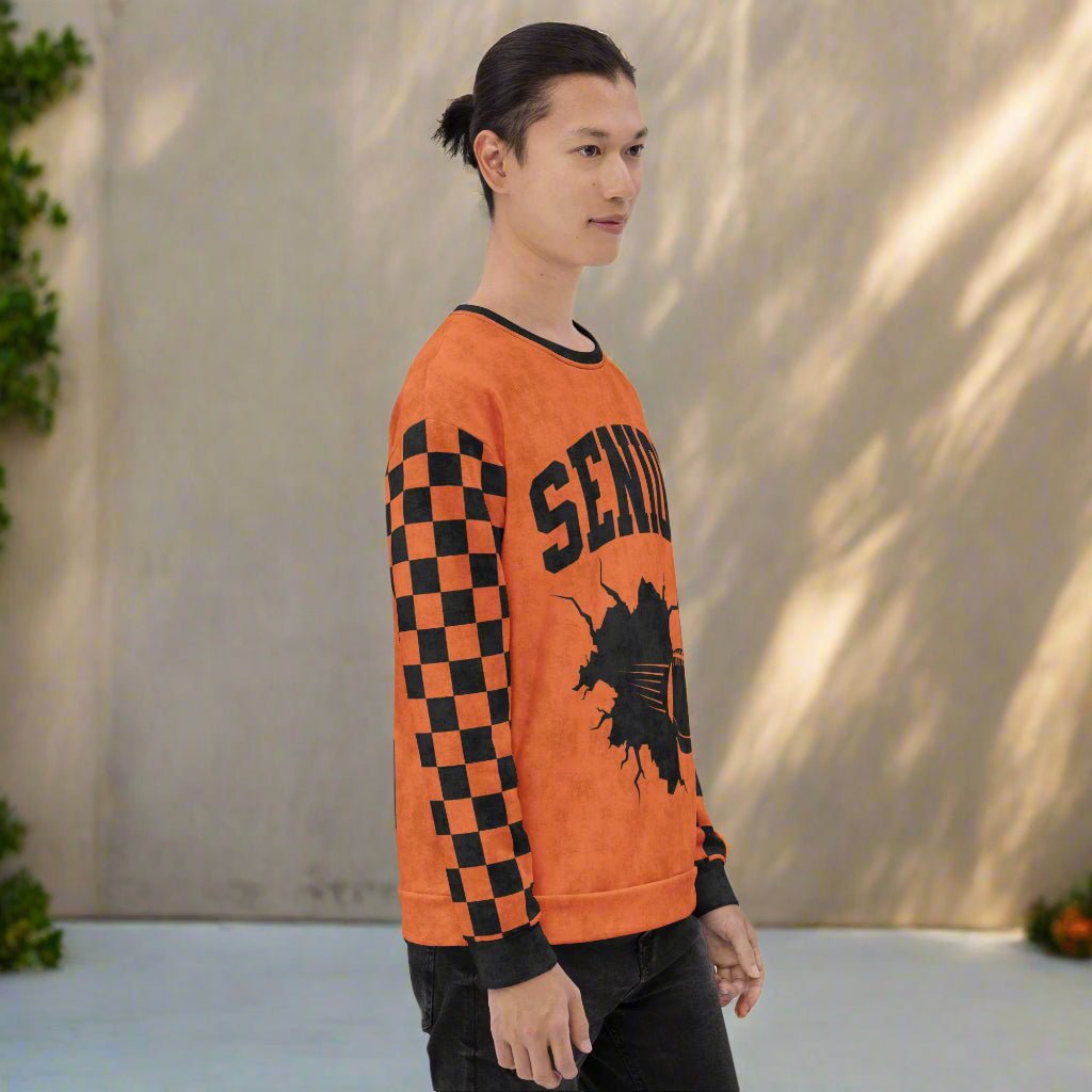 Person wearing an orange sweater with black checkered sleeves and 'SENIOR' text with a football design