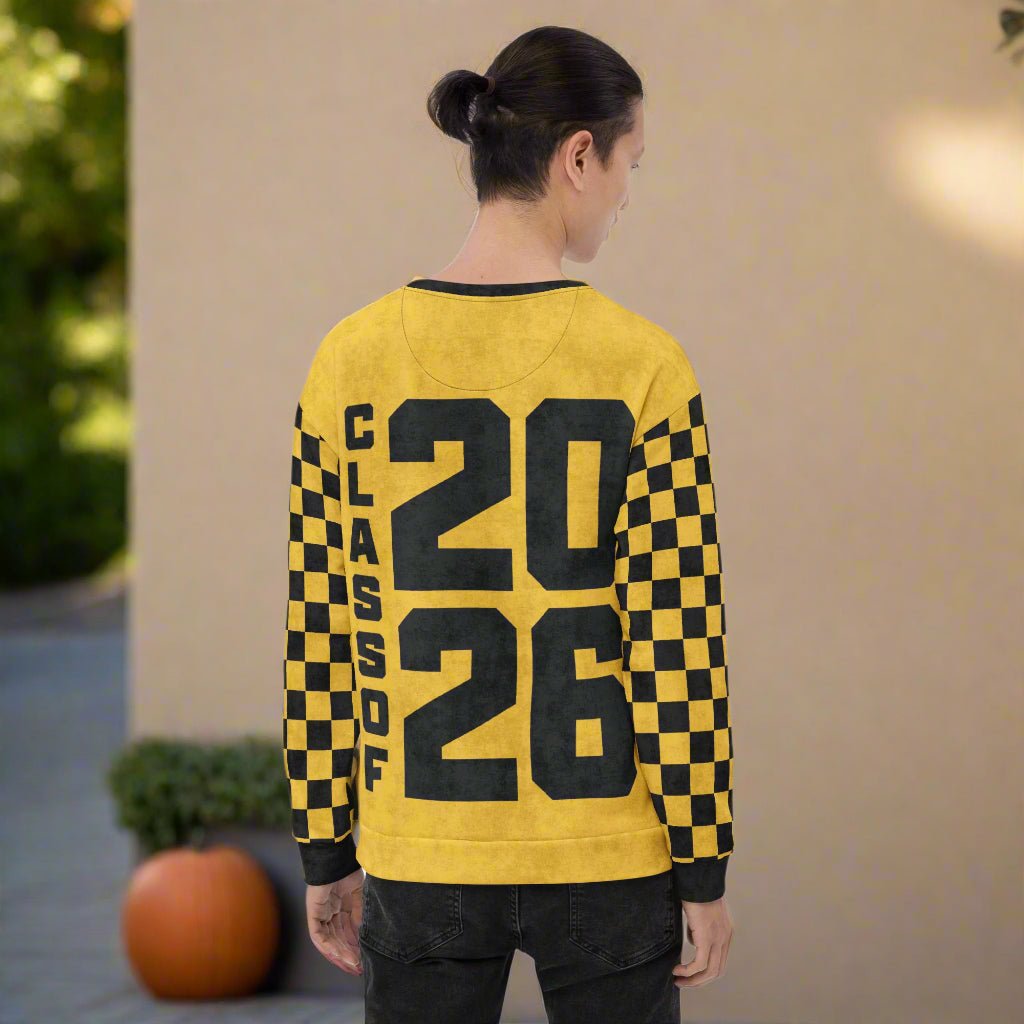 Person wearing a yellow sweatshirt with black Class of 2026 and checkered sleeves