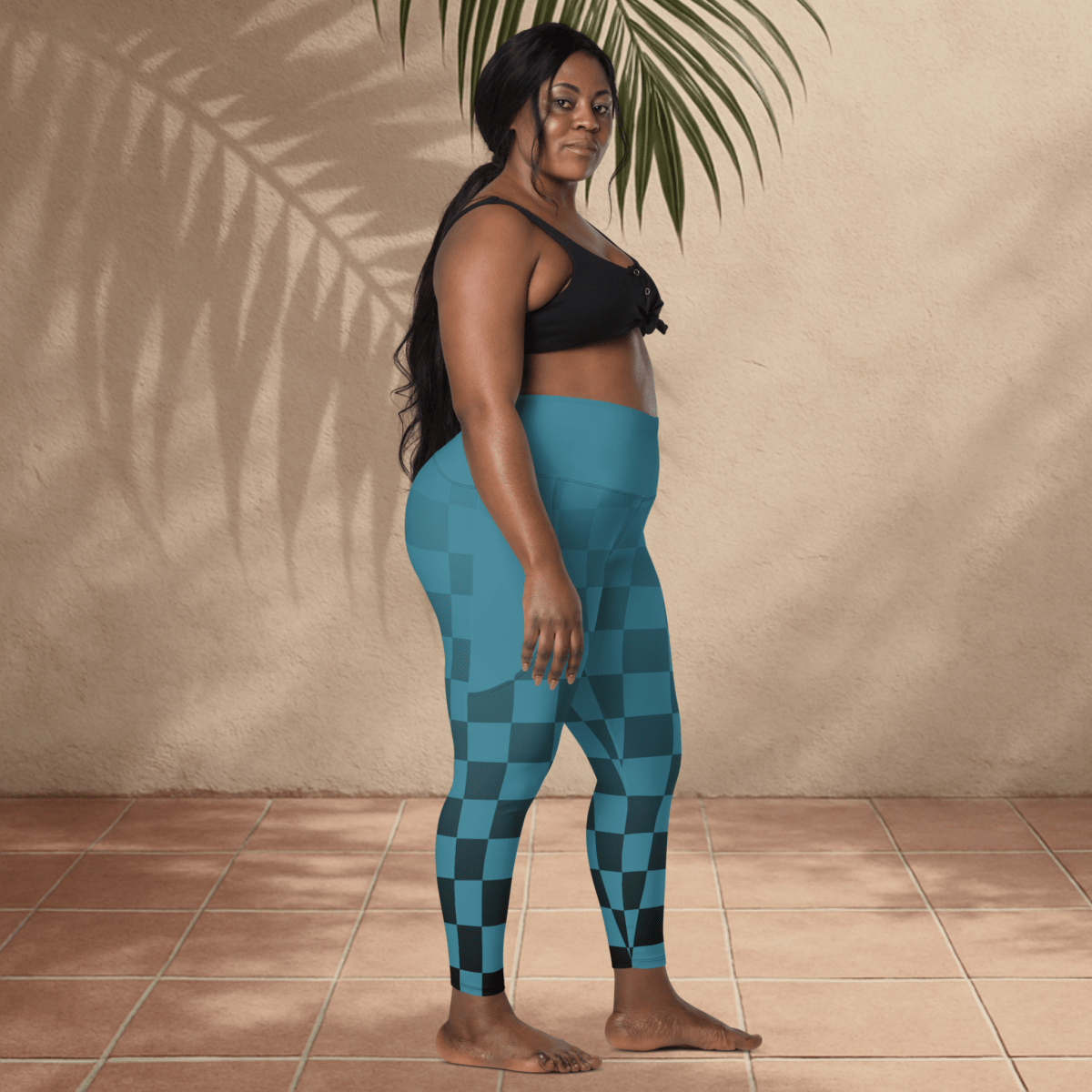 Woman wearing blue checkered leggings standing against a beige wall.
