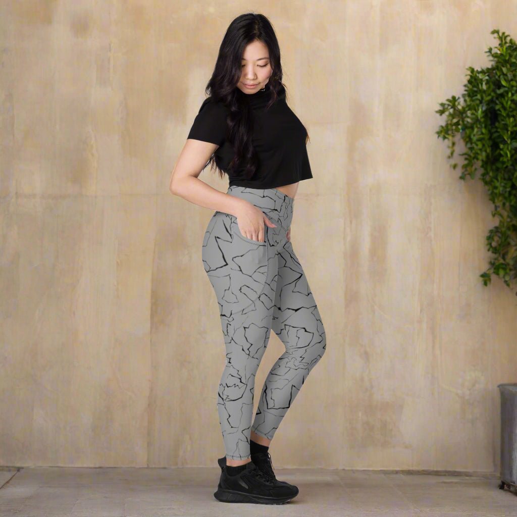 Woman wearing gray patterned leggings and black top on a neutral background