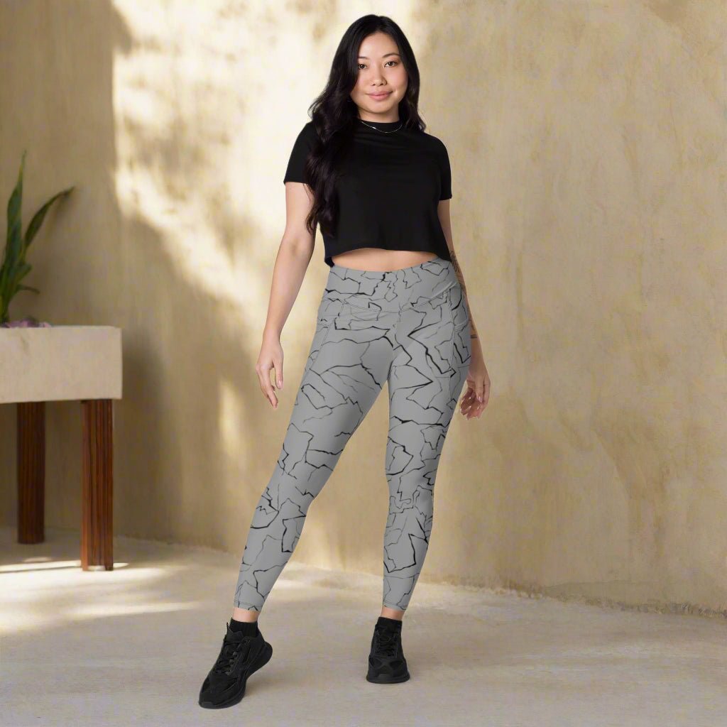 Woman wearing gray patterned leggings and black top on a neutral background
