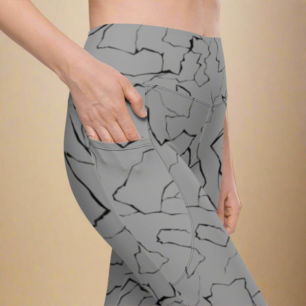 Gray leggings with black abstract pattern worn by a person on a beige background
