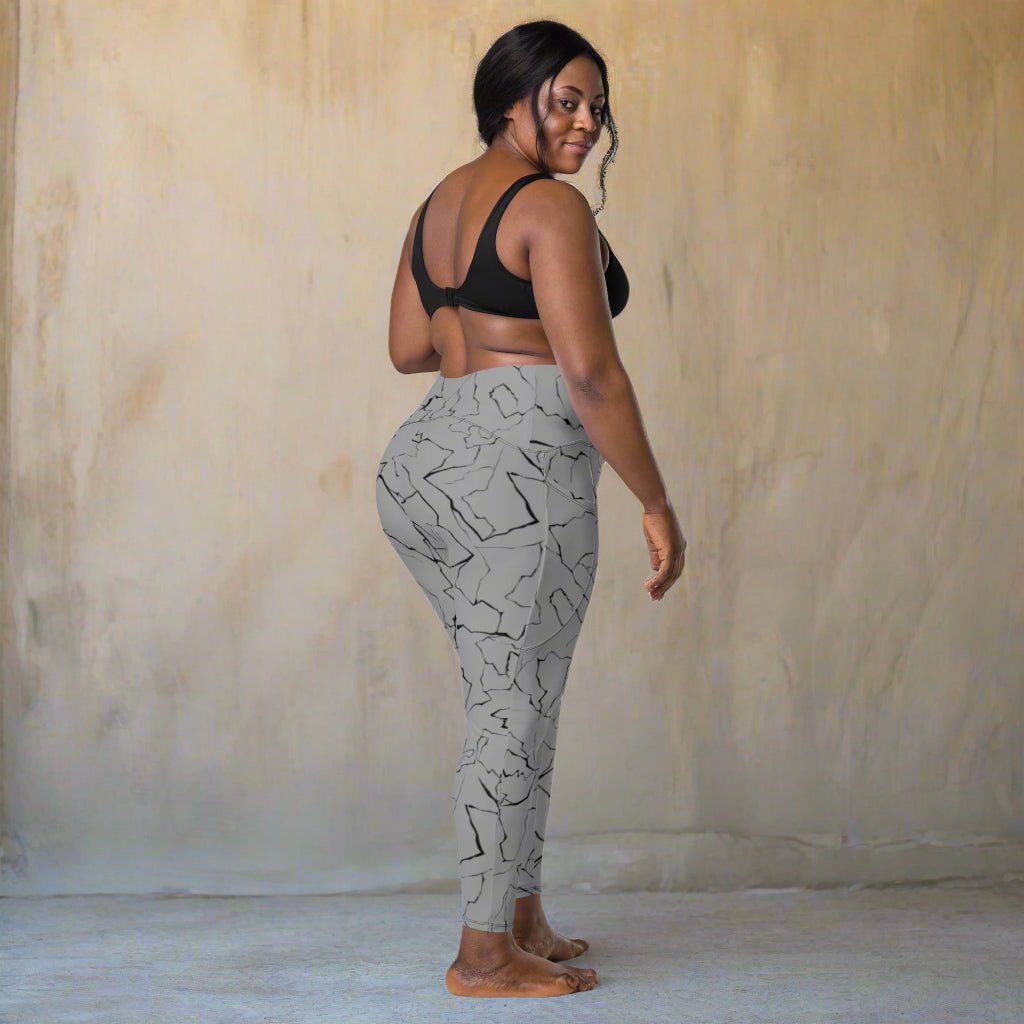 Woman wearing gray patterned leggings and black sports bra on a beige background