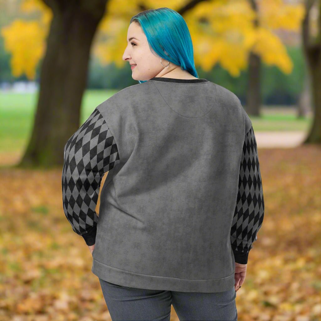 Person wearing a gray sweatshirt with black and gray argyle patterned sleeves outdoors