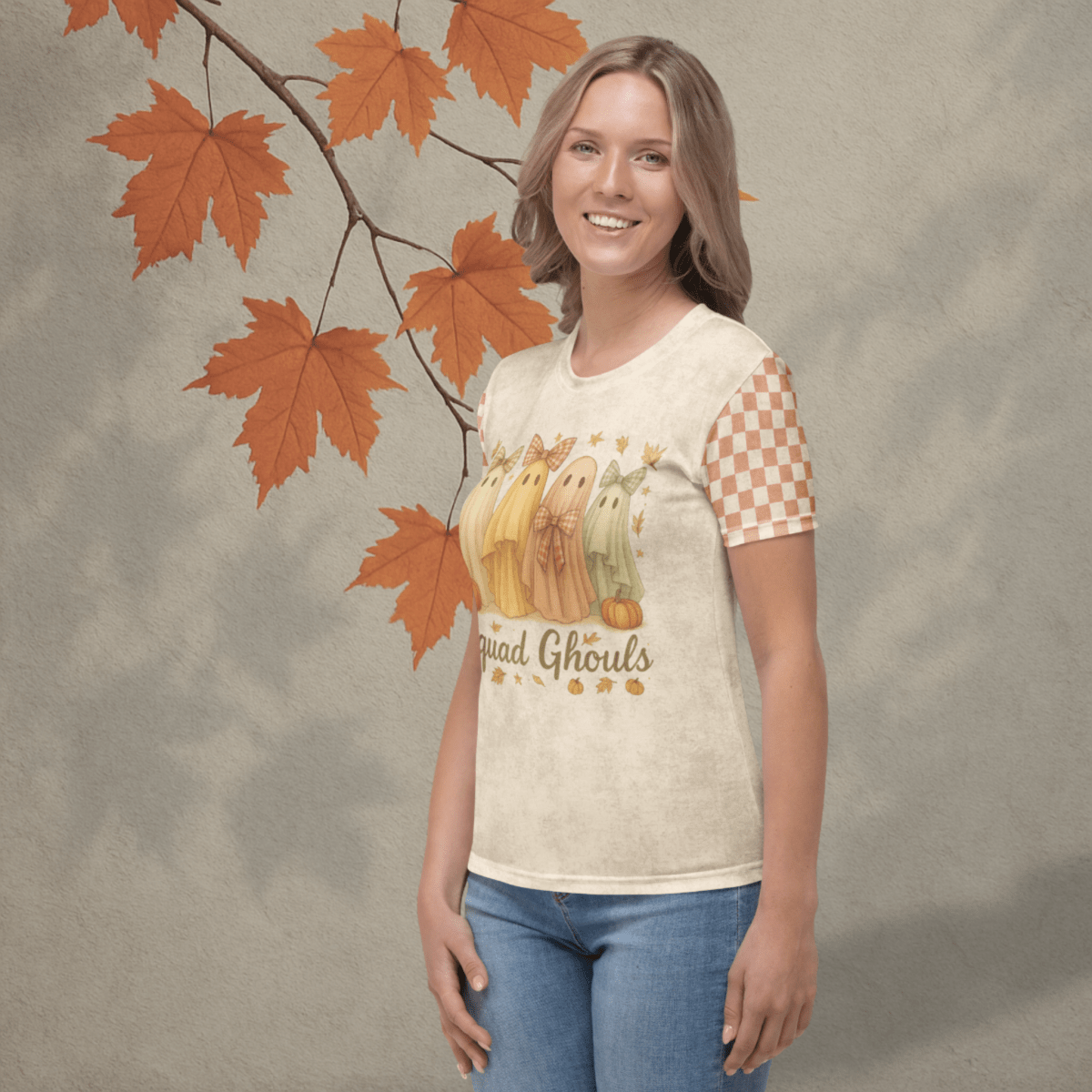 Woman wearing a t-shirt with a checkered sleeve and autumn-themed design, standing against a textured wall with orange leaves.