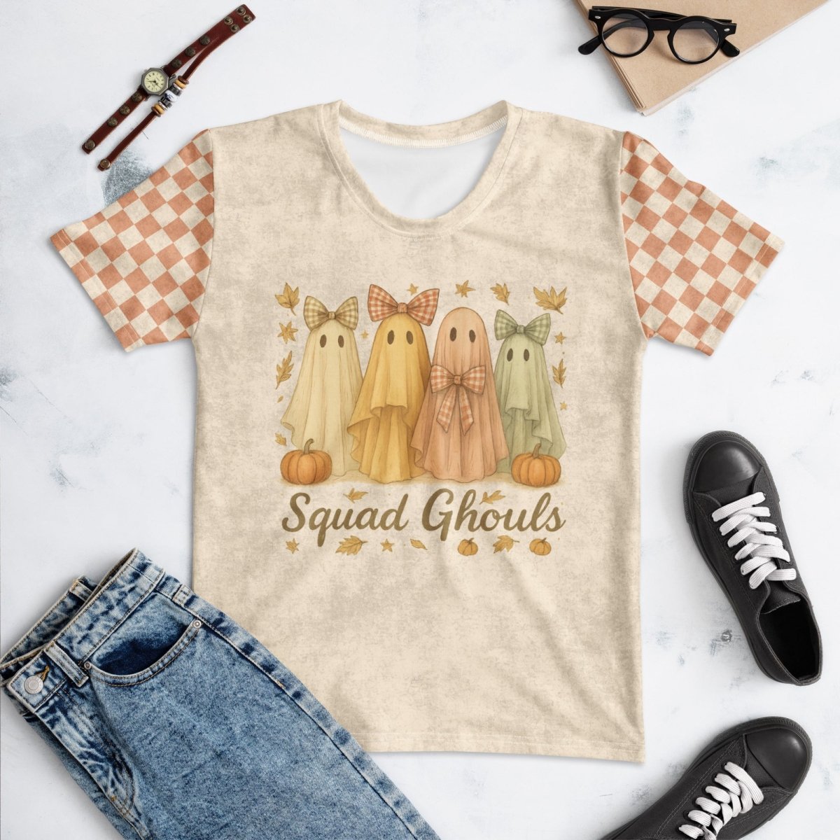 Beige t-shirt with ghost design and 'Squad Ghouls' text on a marble surface with jeans and sneakers.