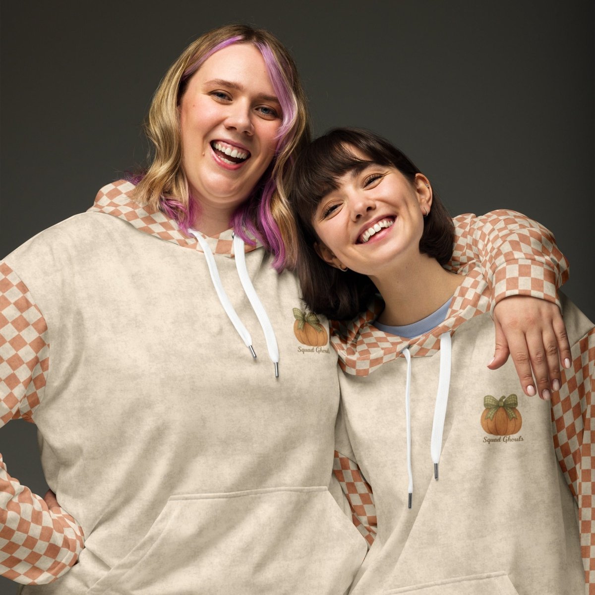 Two people wearing matching hoodies with a checkered pattern on a dark background