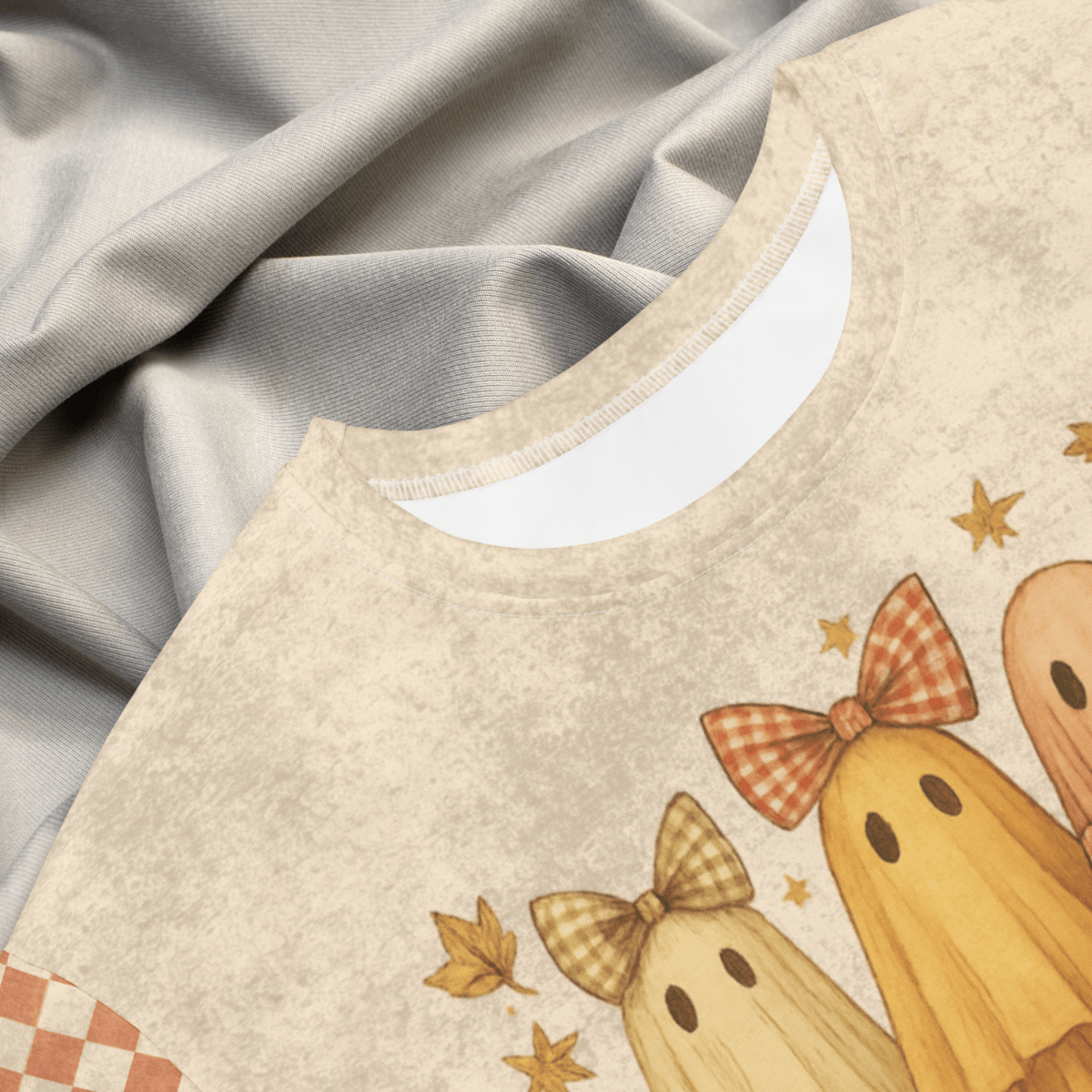 Beige dress with ghost illustrations and checkered bows on a textured gray background