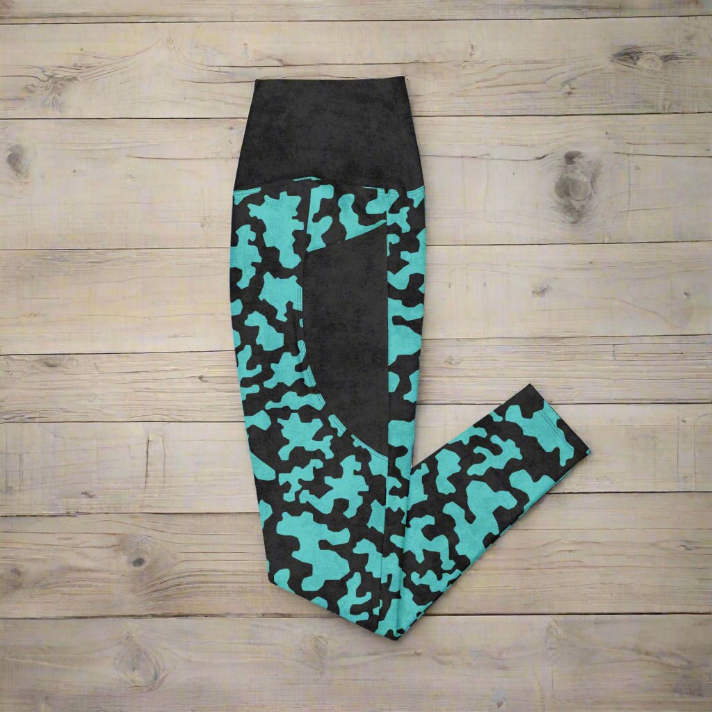 Black leggings with teal camouflage pattern on a wood background