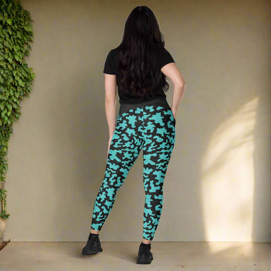 Person wearing black t-shirt and teal camouflage leggings on a neutral background
