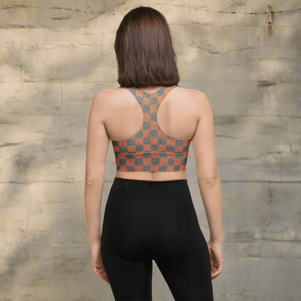 Person wearing a checkered sports bra and black leggings against a textured wall.