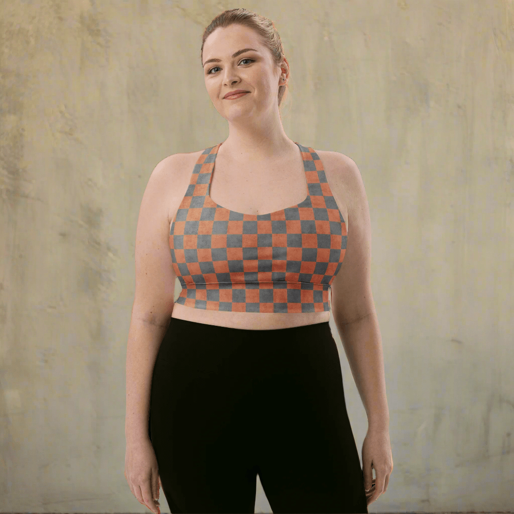 Woman wearing a checkered sports bra and black leggings against a textured beige wall.