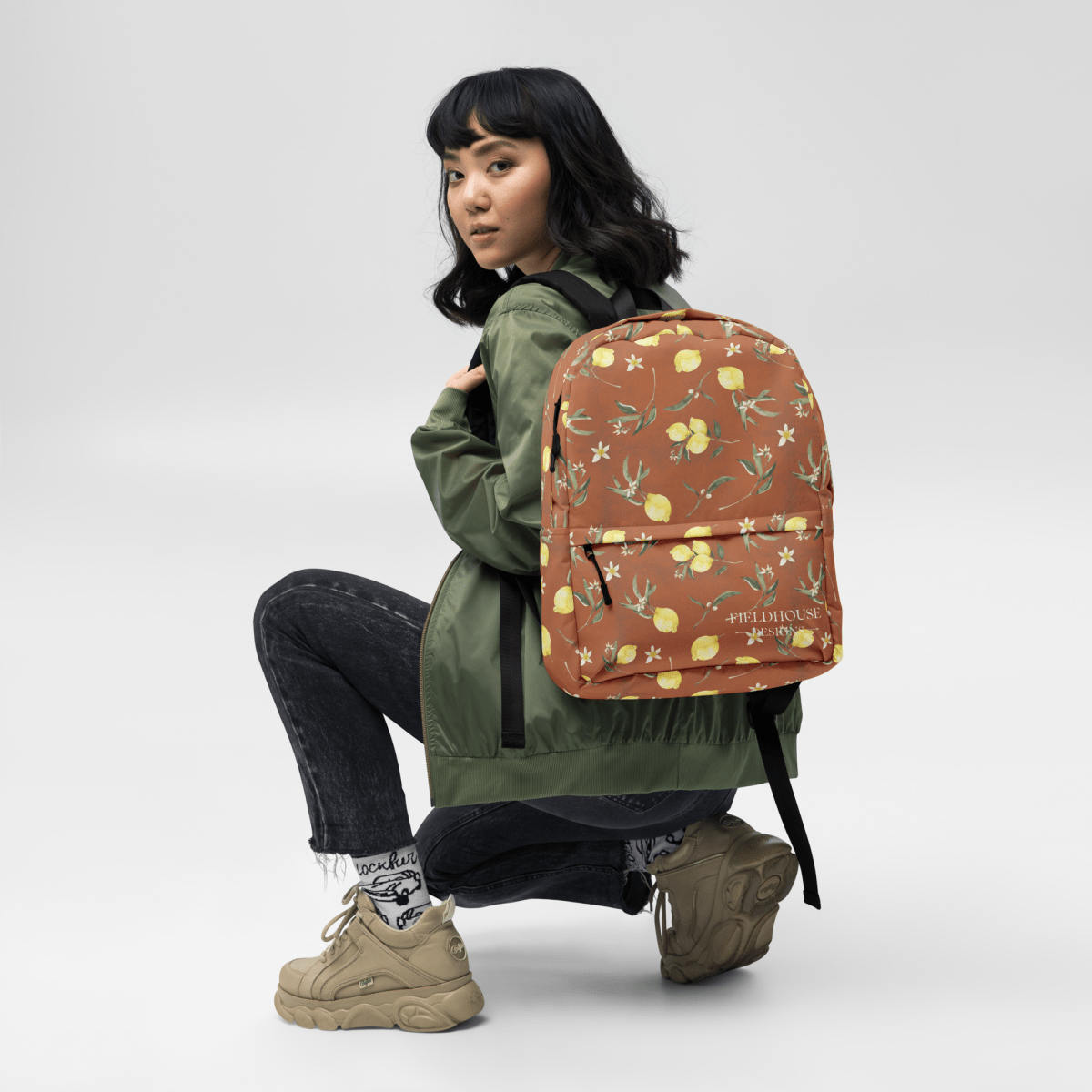 Person wearing a green jacket with a patterned backpack on a white background