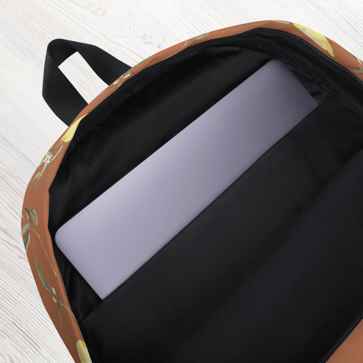 lemon-patterned backpack with a laptop inside on a light wooden surface