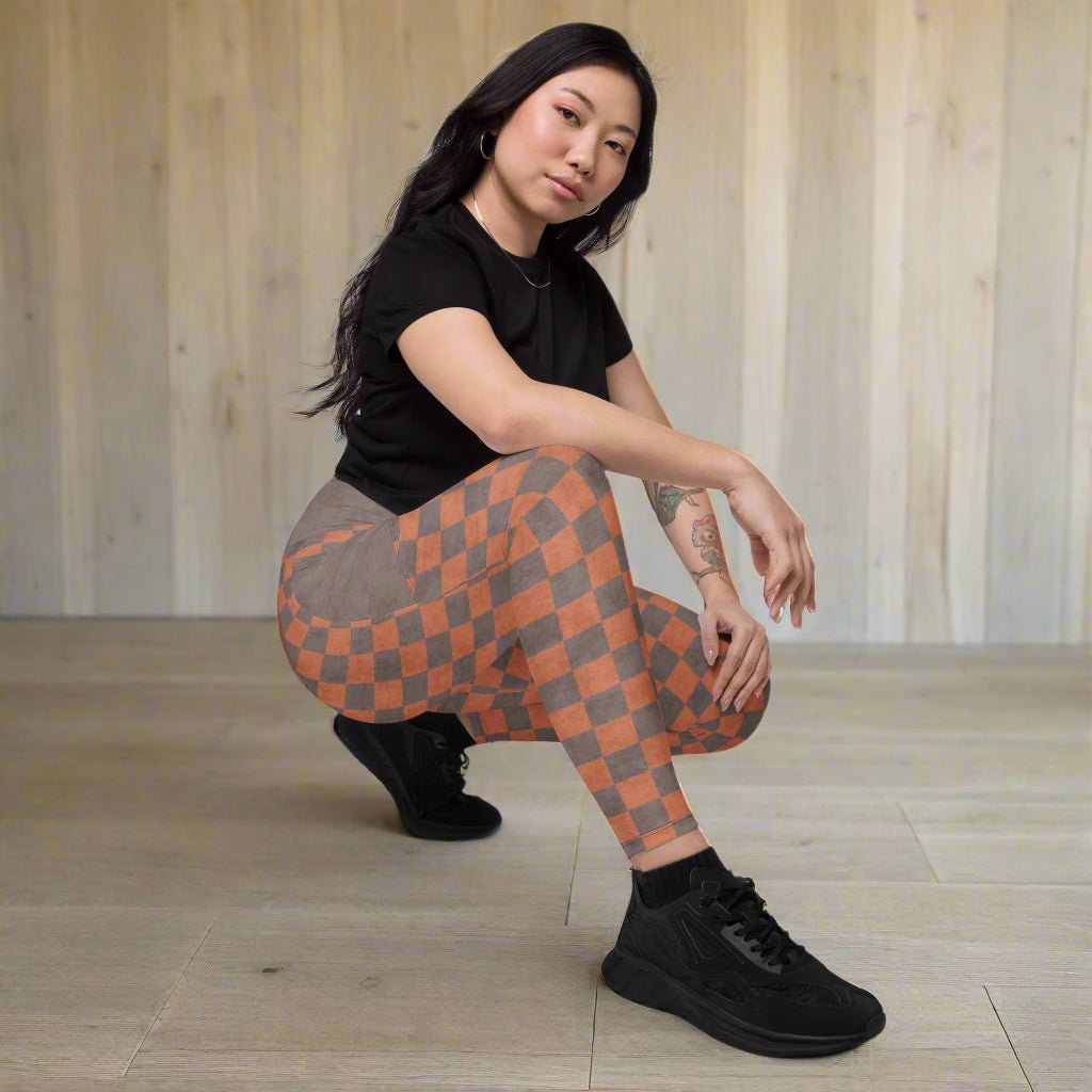 Person wearing a black t-shirt and checkered leggings on a neutral background