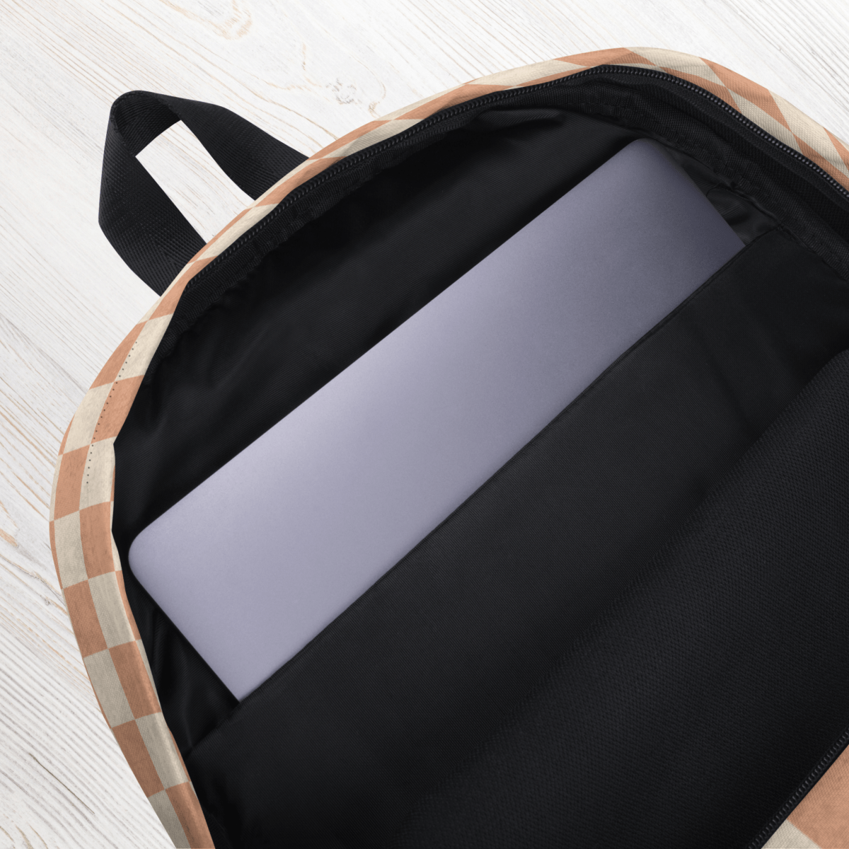 Black laptop sleeve inside a checkered backpack on a light wooden surface