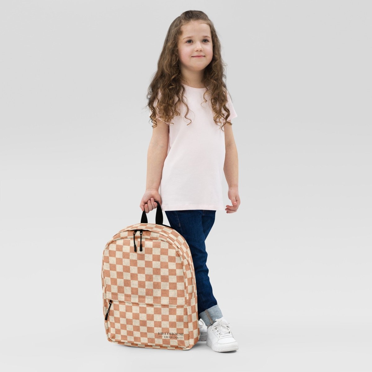 Child holding a checkered backpack against a plain background