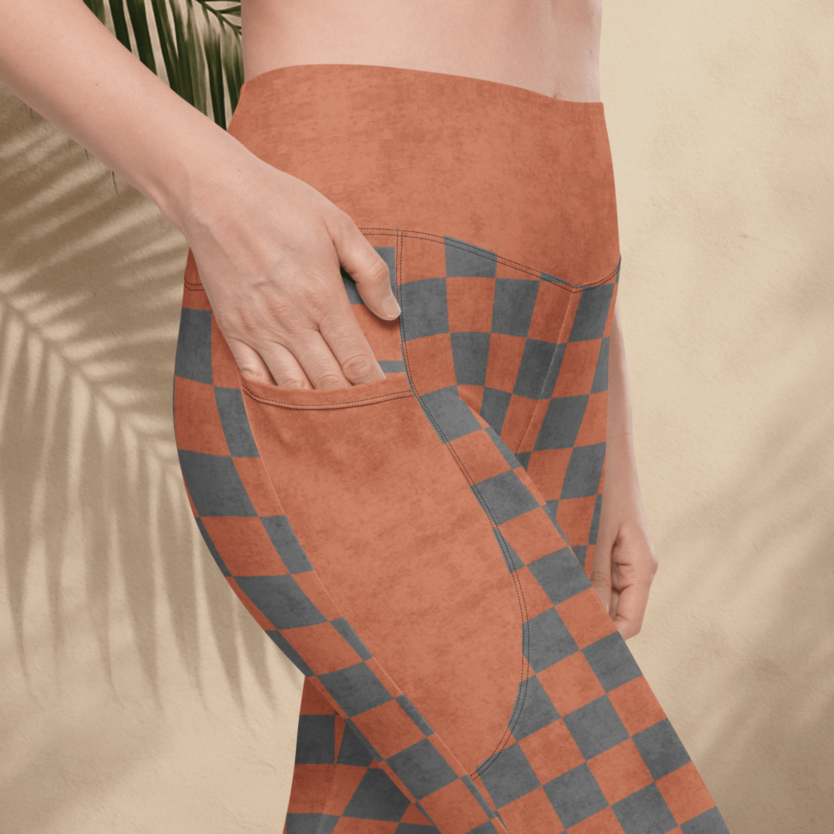 Person wearing terracotta and gray checkered leggings with a beige background