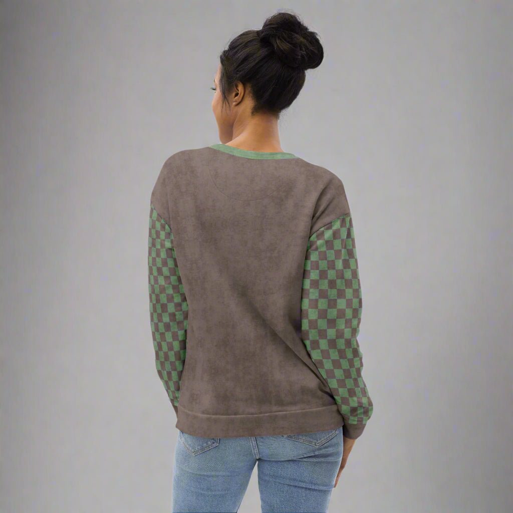 Person wearing a gray sweatshirt with green checkered sleeves on a gray background