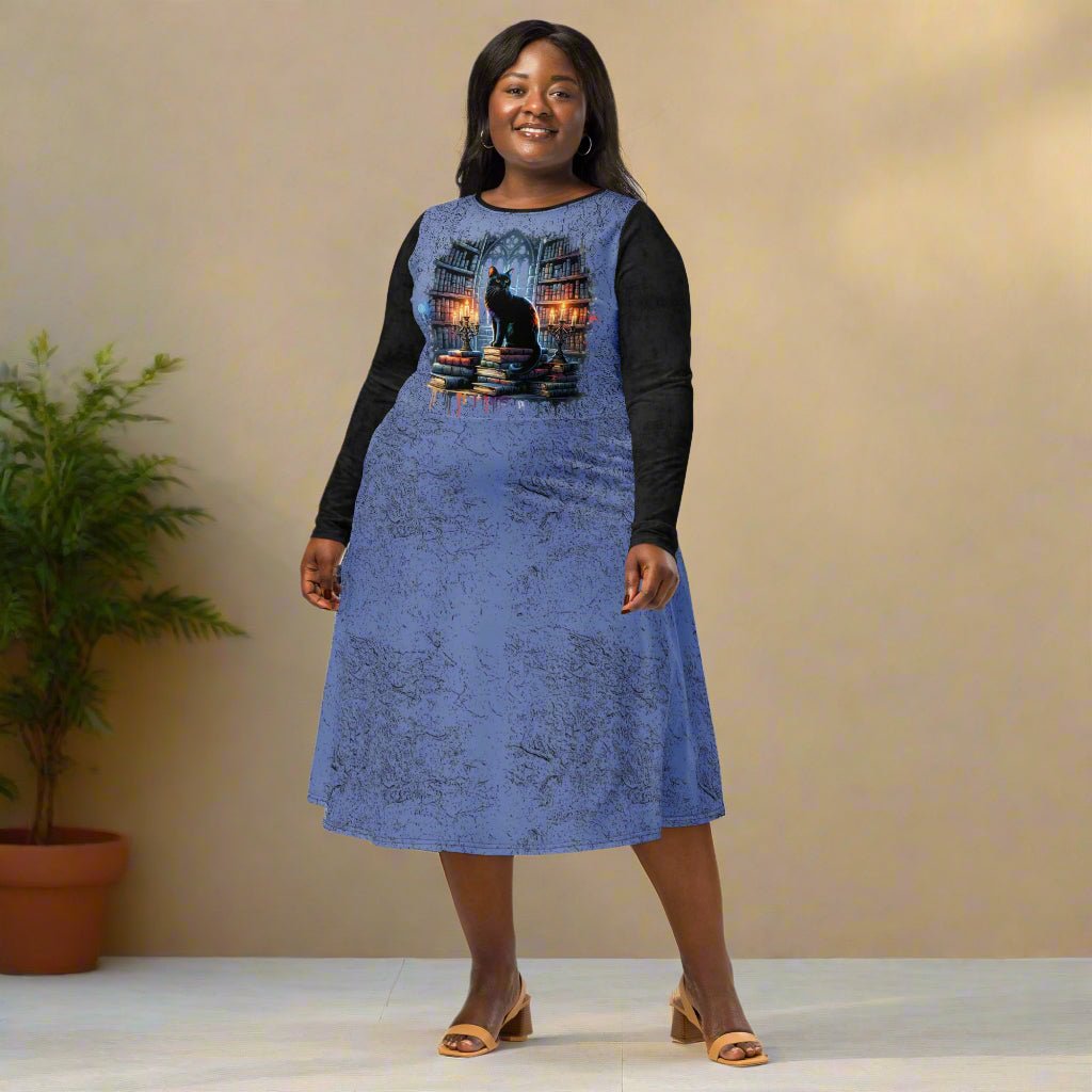 Woman wearing a blue dress with black sleeves and a cat design on a neutral background