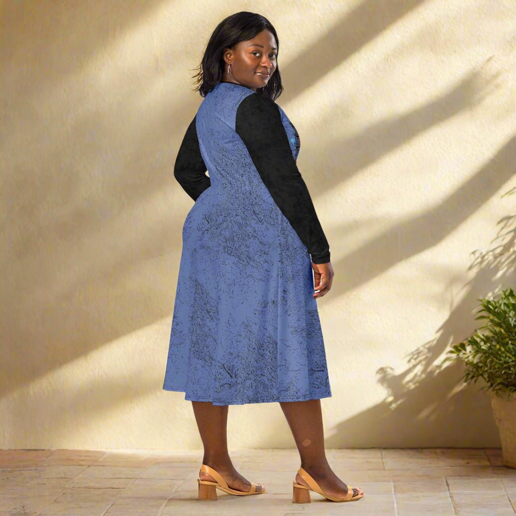 Woman wearing a blue dress with black long-sleeves on a neutral background
