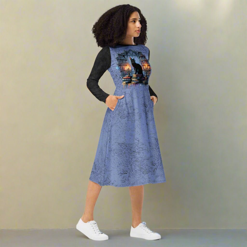 Woman wearing a blue dress with a cat print and black long sleeves against a beige background