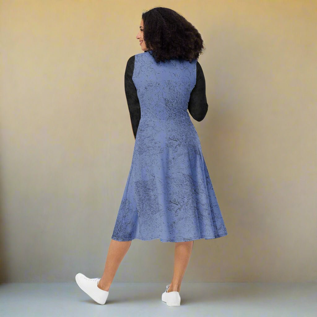 Woman wearing a blue dress with black sleeves against a beige background