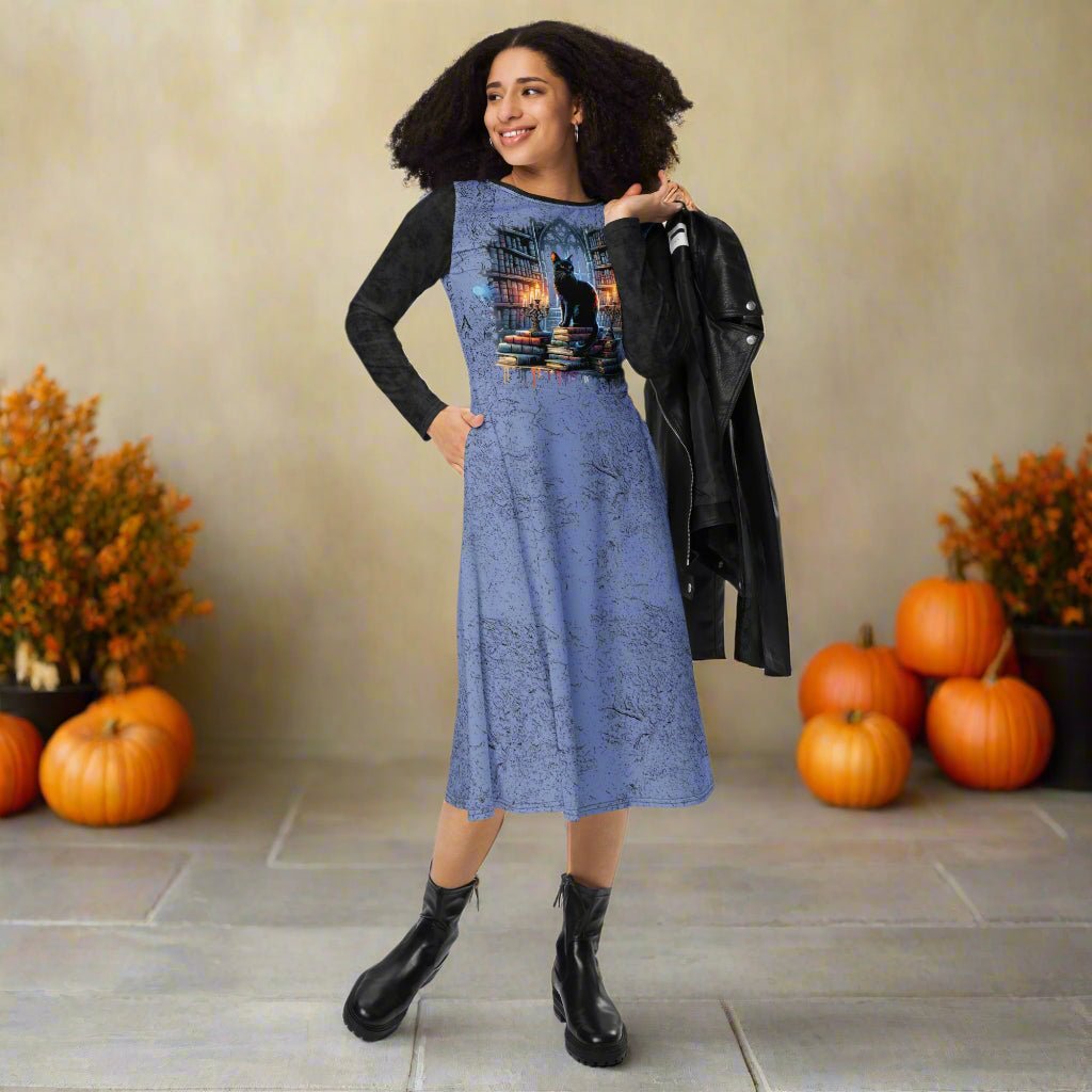 Woman wearing a blue dress with a black cat design, black jacket, and black boots on a fall background