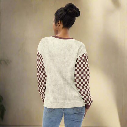 Person wearing a cream sweater with checkered sleeves on a beige background