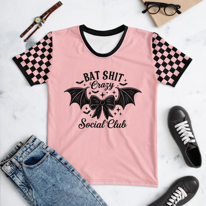 Pink t-shirt with black graphic design and text, surrounded by casual items on a marble surface.