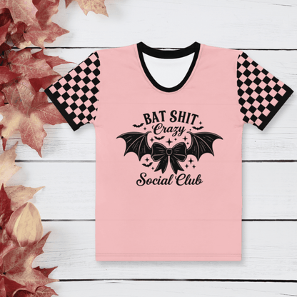 Pink t-shirt with black text and design on a white wooden background with autumn leaves.