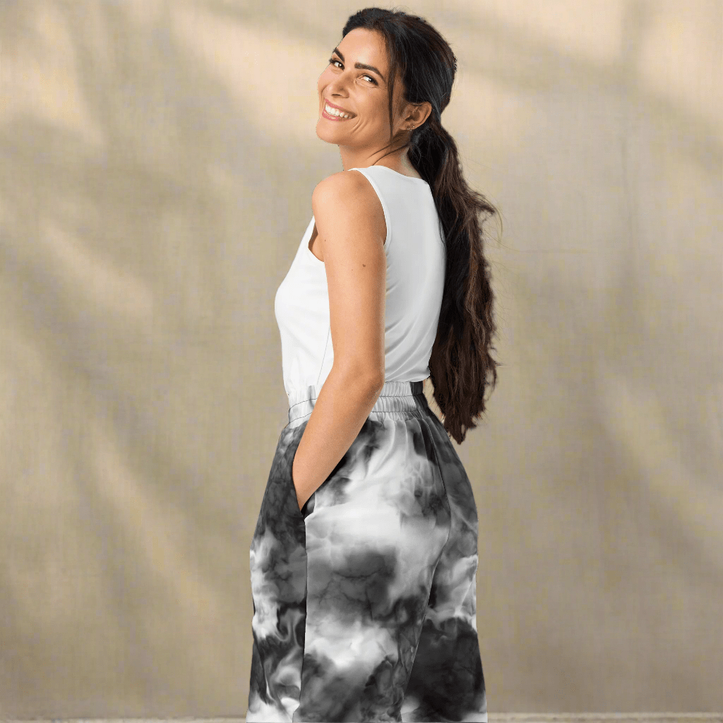 Woman wearing a white sleeveless top and black and white patterned pants against a beige background