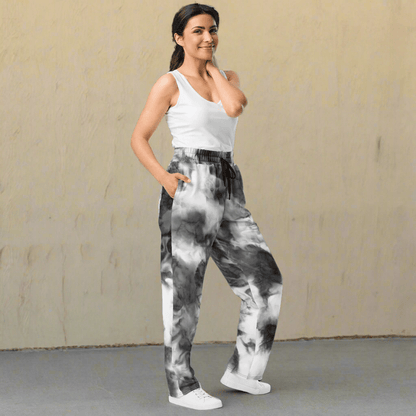 Woman wearing tie-dye pants and a white top on a neutral background