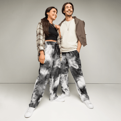 Two people wearing tie-dye pants standing against a plain background