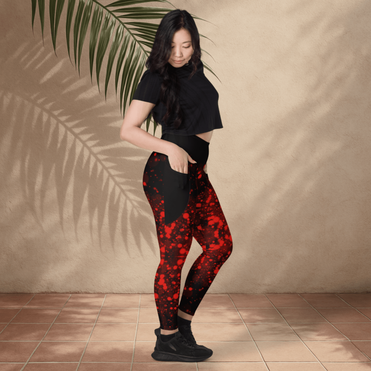 Woman wearing black and red patterned leggings against a beige wall.