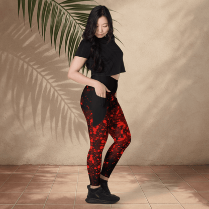Woman wearing black and red patterned leggings against a beige wall.