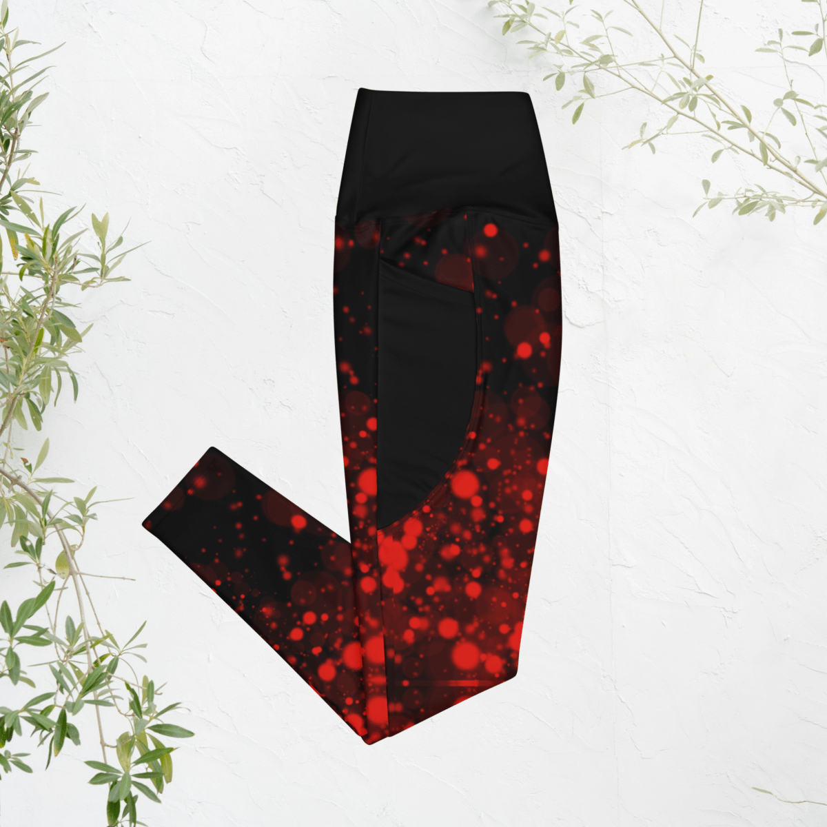 Black and red patterned leggings on a white background with green leaves.