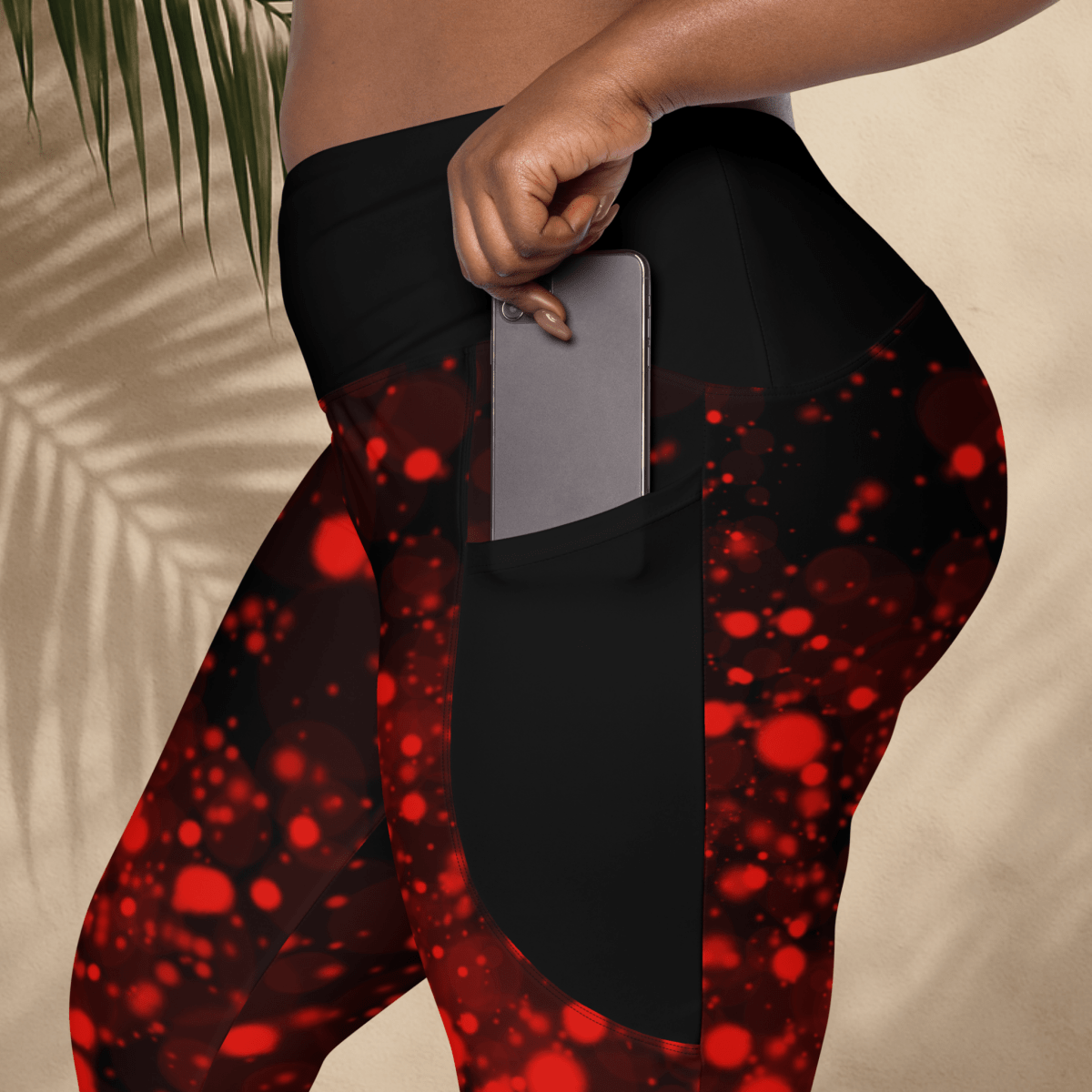Black leggings with red abstract pattern worn by a person, held against a neutral background.