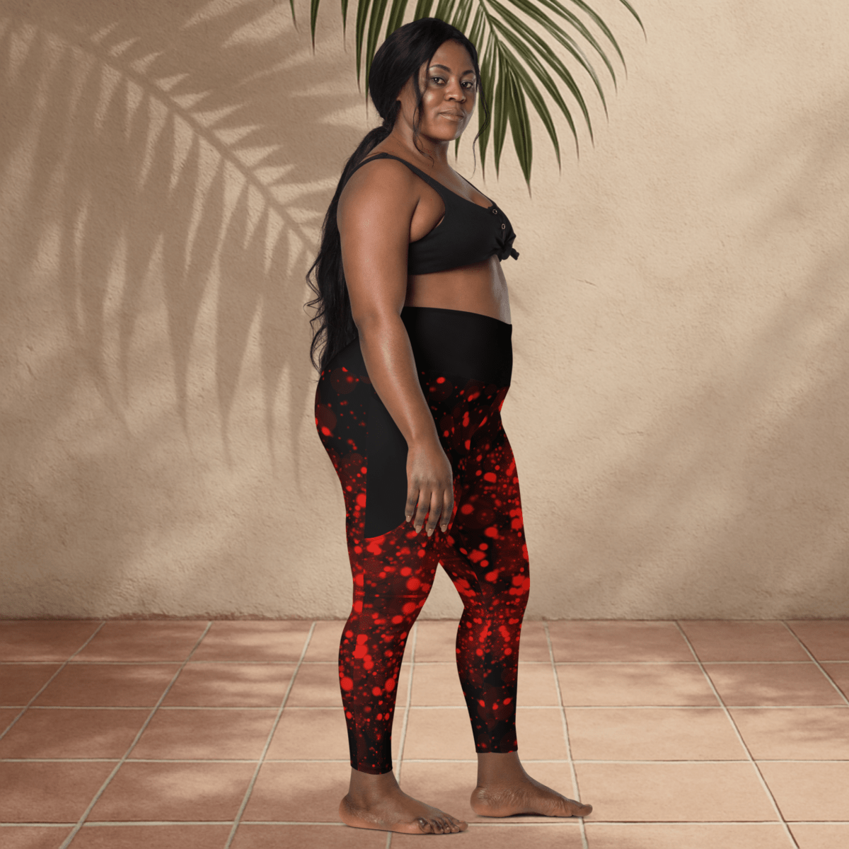 Woman wearing black and red patterned leggings standing against a beige wall.