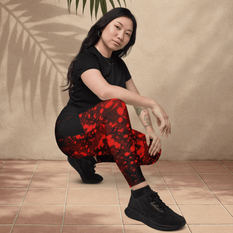 Person wearing black and red outfit posing against a beige wall with a palm leaf