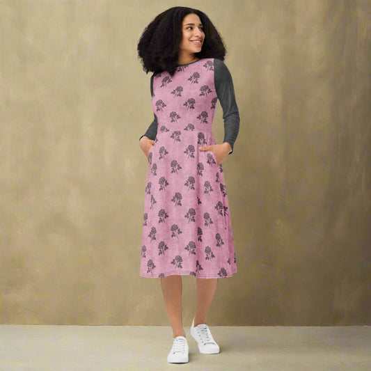 Woman wearing a pink dress with charcoal floral pattern on a neutral background