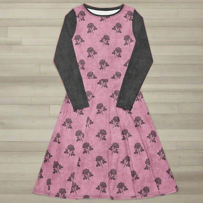 Pink dress with charcoal floral pattern and long sleeves on a wood background
