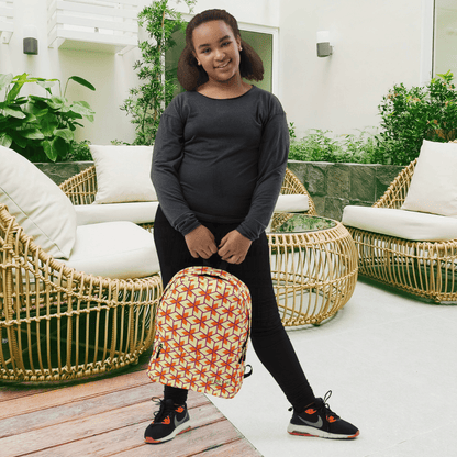 Person holding a patterned backpack in an outdoor setting with wicker furniture and plants.