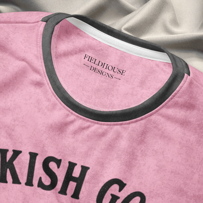 Pink shirt with black text and neckline trim on a textured fabric background