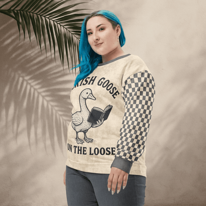 Person wearing a sweater with a goose graphic and text, standing against a neutral background with a leaf.
